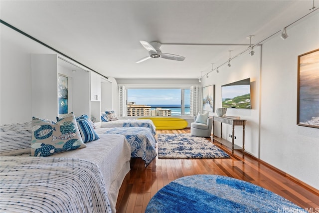 bedroom with hardwood / wood-style floors, track lighting, and ceiling fan