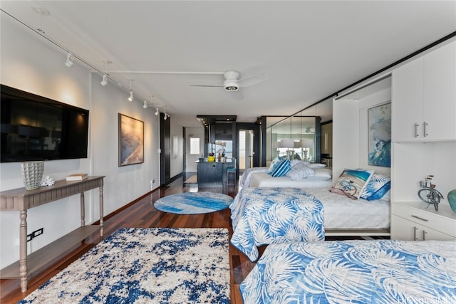 bedroom with ceiling fan, rail lighting, and dark hardwood / wood-style flooring