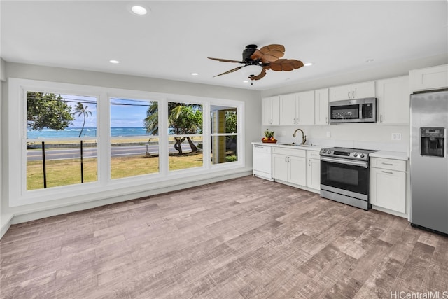 kitchen featuring sink, stainless steel appliances, light hardwood / wood-style flooring, and white cabinets