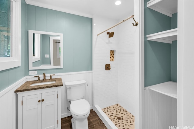 bathroom with toilet, crown molding, and tiled shower