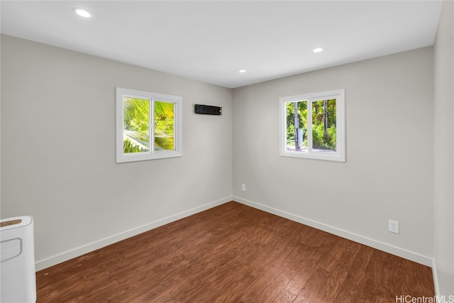 unfurnished room featuring a healthy amount of sunlight and dark hardwood / wood-style floors