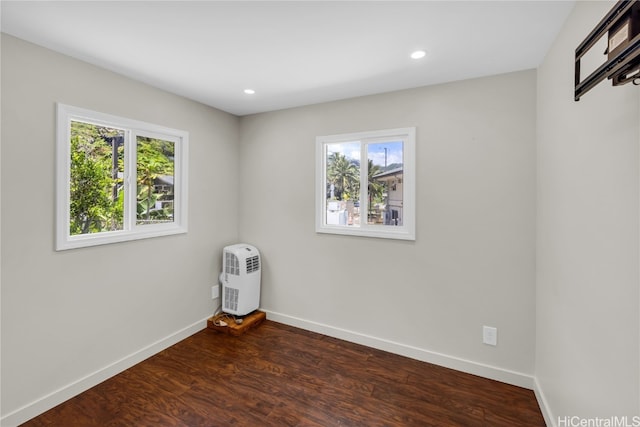 empty room featuring dark hardwood / wood-style floors, heating unit, and a wealth of natural light