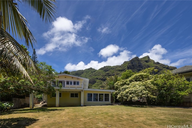 back of house with a mountain view, a yard, and a balcony