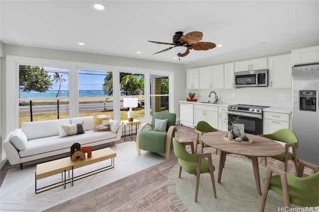 living room featuring light parquet floors, sink, a water view, and ceiling fan