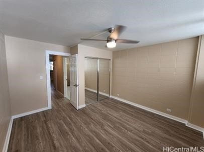 unfurnished bedroom with a closet, dark hardwood / wood-style floors, and ceiling fan