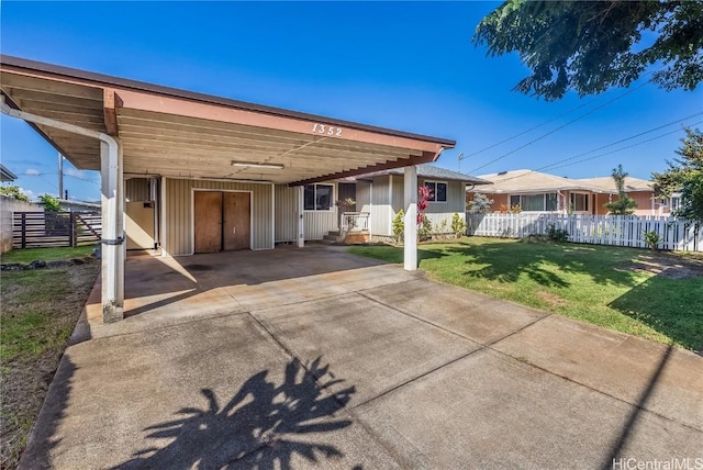 rear view of property with a carport and a yard