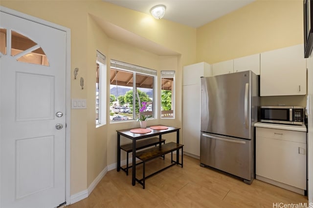 kitchen with appliances with stainless steel finishes, white cabinets, and light wood-type flooring