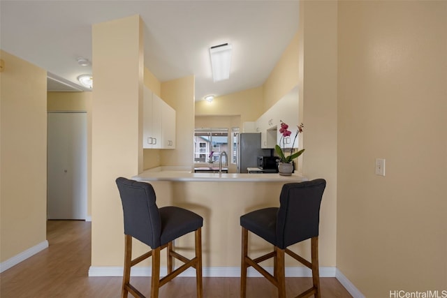 kitchen featuring white cabinetry, lofted ceiling, light hardwood / wood-style floors, and kitchen peninsula