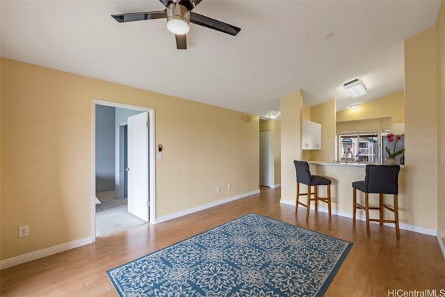 interior space with a breakfast bar, vaulted ceiling, light wood-type flooring, kitchen peninsula, and white cabinets