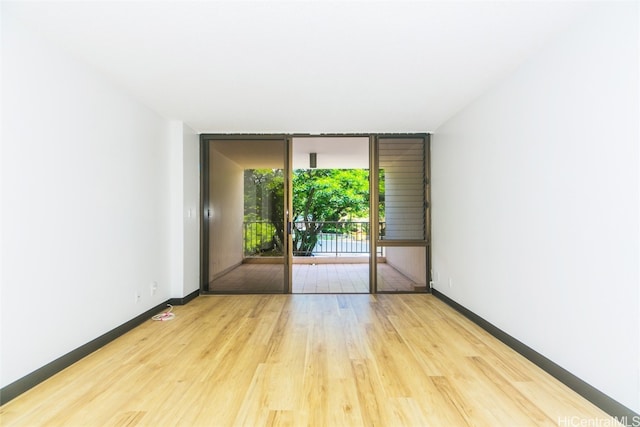 unfurnished room featuring light hardwood / wood-style floors and a wall of windows