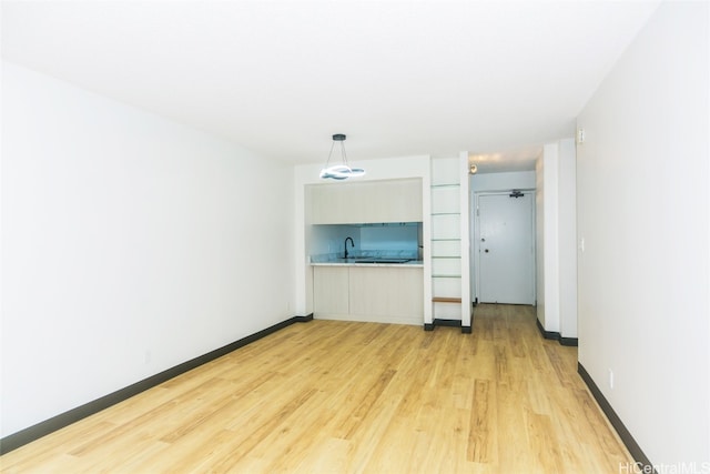 unfurnished living room featuring sink and light hardwood / wood-style floors