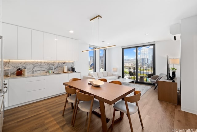 dining space featuring hardwood / wood-style floors, expansive windows, a wall mounted air conditioner, and sink