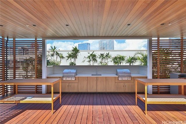 wooden deck with an outdoor kitchen, area for grilling, and sink