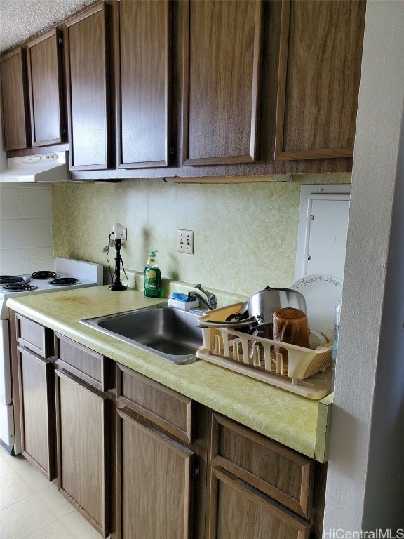 kitchen featuring dark brown cabinets, backsplash, range hood, sink, and white range with electric stovetop