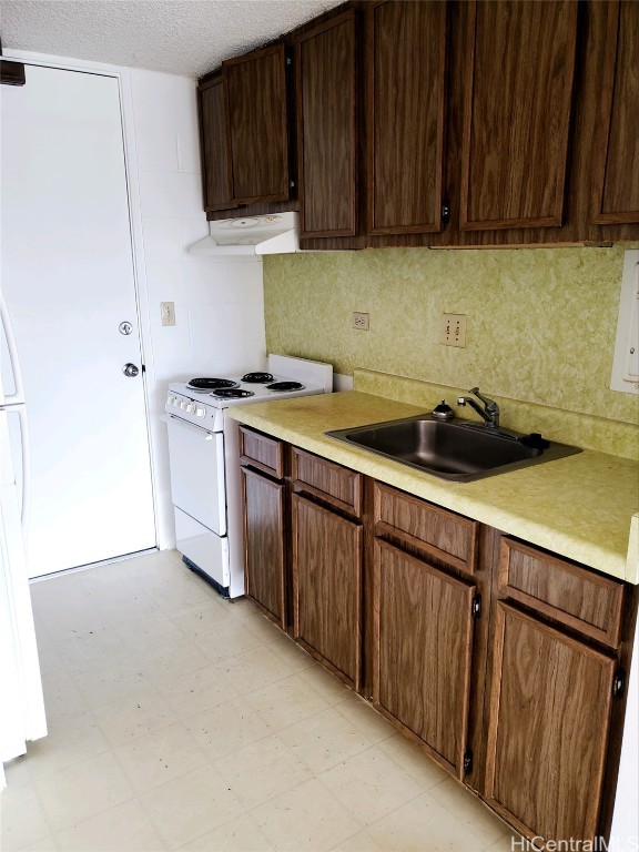 kitchen featuring a textured ceiling, white range oven, dark brown cabinetry, sink, and ventilation hood