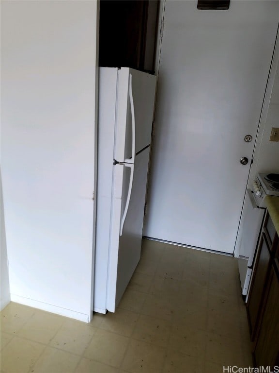 kitchen with white fridge and dark brown cabinets