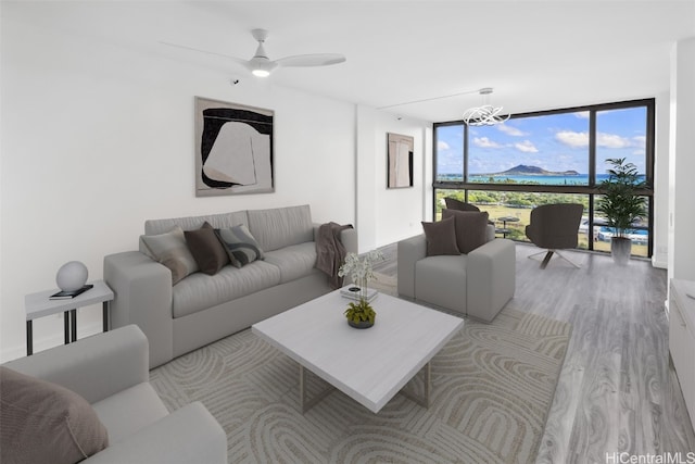 living room featuring expansive windows, ceiling fan with notable chandelier, and light wood-type flooring