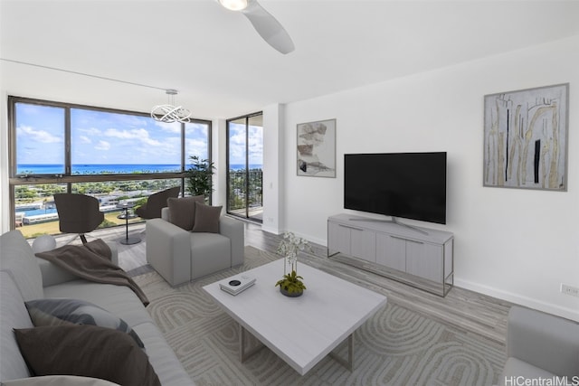 living room with a water view, ceiling fan with notable chandelier, and plenty of natural light