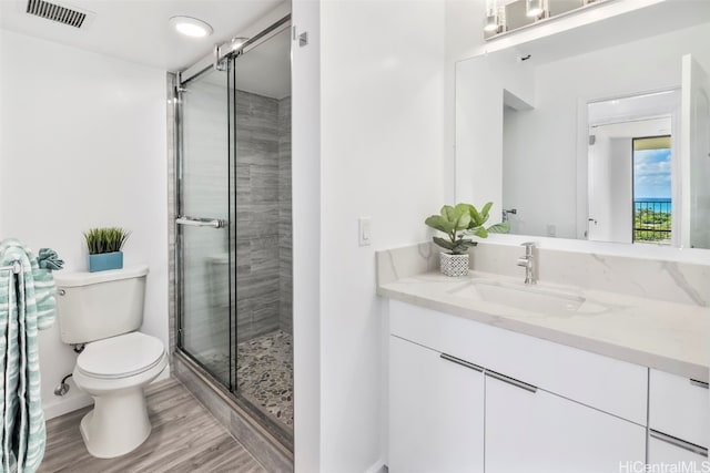 bathroom with vanity, a shower with shower door, hardwood / wood-style flooring, and toilet