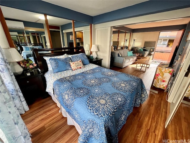 bedroom featuring a wall unit AC, wood-type flooring, and a closet