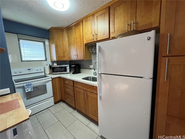 kitchen with white appliances, backsplash, a textured ceiling, and sink