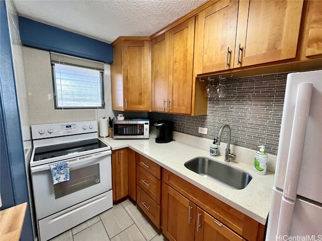 kitchen with light stone countertops, sink, backsplash, and white appliances