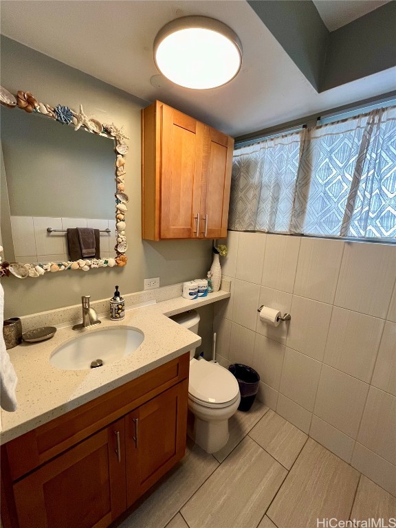 bathroom featuring toilet, vanity, and tile walls