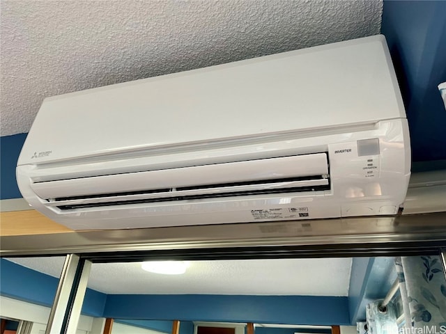 details with a wall unit AC and a textured ceiling