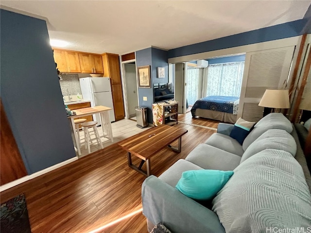 living room featuring a wall mounted AC and light wood-type flooring