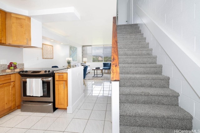 kitchen featuring light stone countertops, light tile patterned flooring, and stainless steel range with electric stovetop