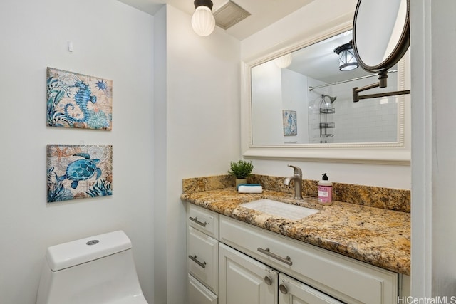 bathroom featuring vanity, tiled shower, and toilet