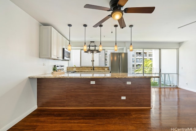 kitchen featuring light stone countertops, kitchen peninsula, stainless steel appliances, and dark hardwood / wood-style flooring