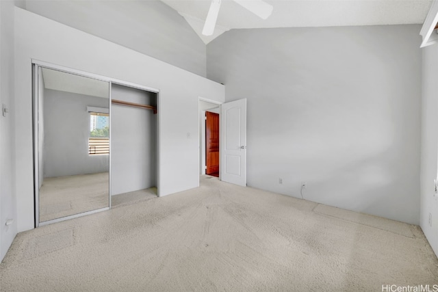 unfurnished bedroom featuring light carpet, a closet, high vaulted ceiling, and ceiling fan