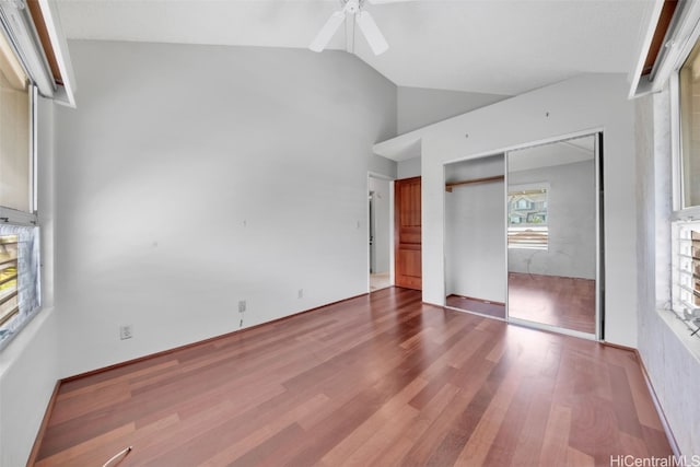 unfurnished bedroom with multiple windows, hardwood / wood-style floors, a closet, and lofted ceiling