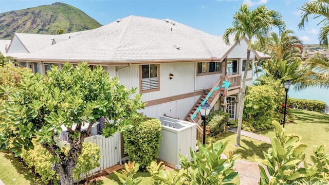 rear view of property with central air condition unit, a lawn, and a mountain view