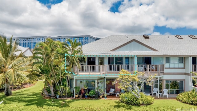 rear view of property featuring a yard and a balcony