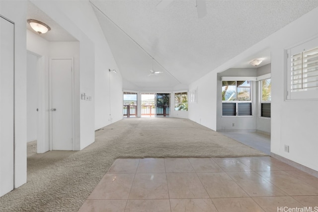 corridor featuring a wealth of natural light, lofted ceiling, a textured ceiling, and light colored carpet