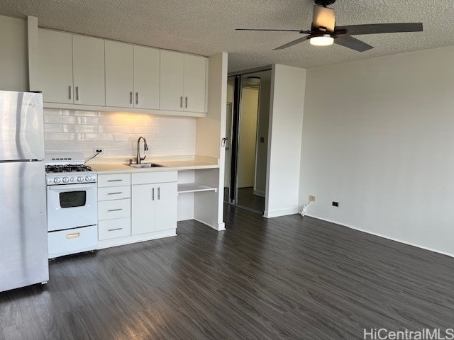 kitchen with white cabinets, a textured ceiling, white appliances, and dark hardwood / wood-style flooring