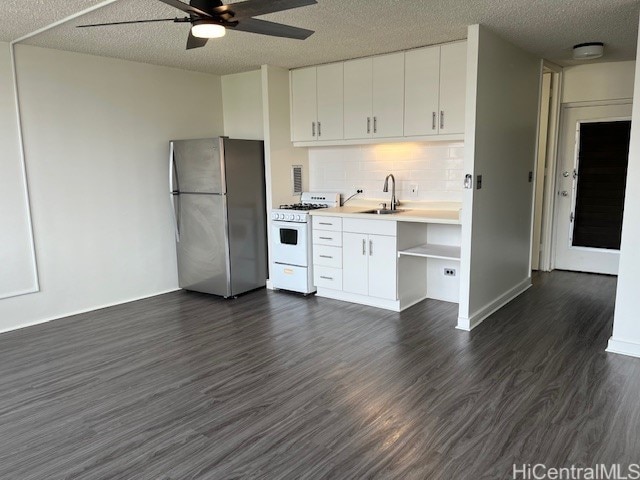 kitchen with sink, white gas range oven, white cabinetry, dark wood-type flooring, and stainless steel refrigerator