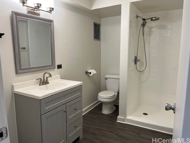 bathroom featuring vanity, hardwood / wood-style floors, tiled shower, and toilet