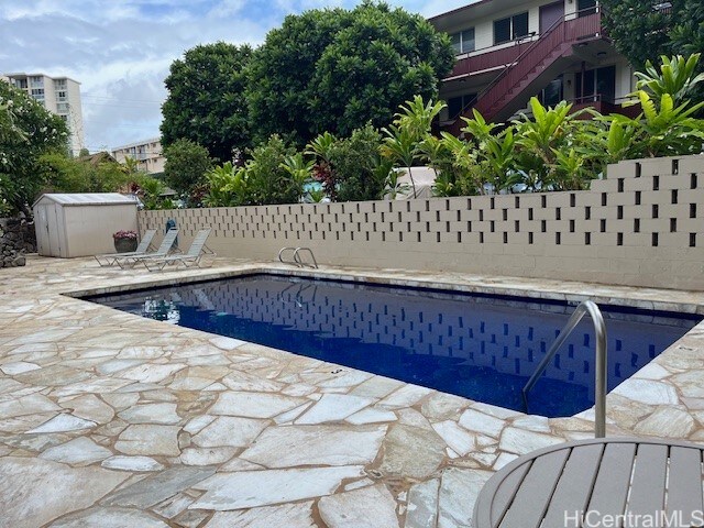 view of swimming pool featuring a patio and a storage unit