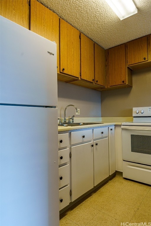 kitchen with a textured ceiling, sink, and white appliances