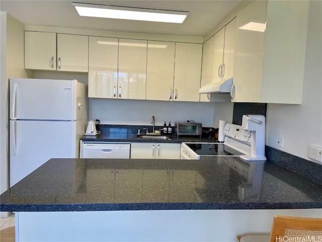 kitchen featuring sink, kitchen peninsula, white appliances, and dark stone counters