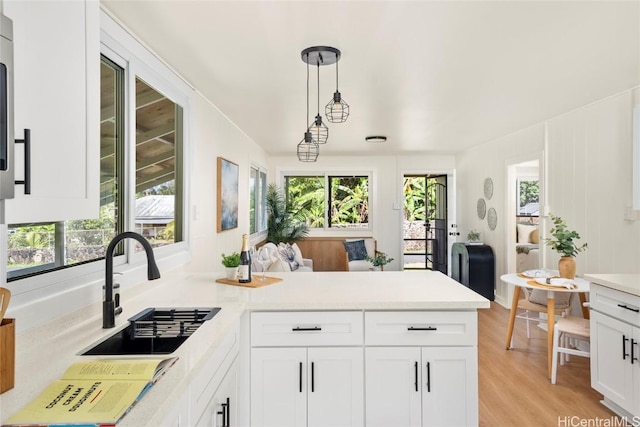 kitchen with a peninsula, a sink, light countertops, white cabinets, and open floor plan