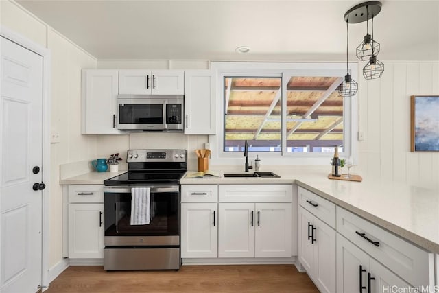 kitchen featuring light wood-style flooring, a sink, light countertops, white cabinets, and appliances with stainless steel finishes