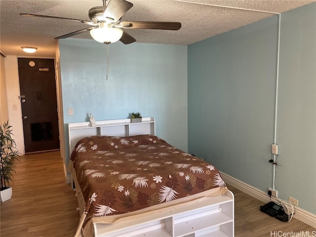 bedroom featuring ceiling fan, hardwood / wood-style floors, and a textured ceiling