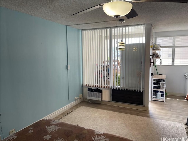 spare room with a textured ceiling, ceiling fan, hardwood / wood-style floors, and an AC wall unit