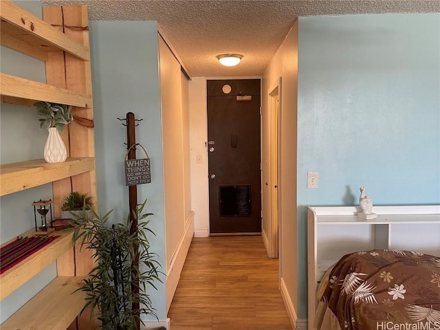 hall featuring a textured ceiling and light hardwood / wood-style flooring