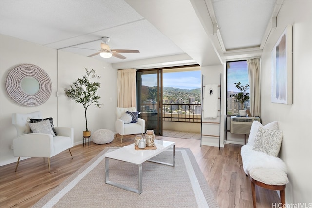 sitting room featuring a mountain view, hardwood / wood-style flooring, and ceiling fan