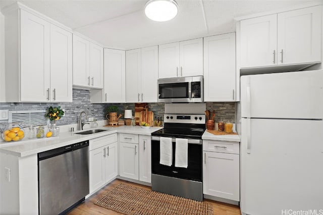 kitchen with sink, white cabinetry, appliances with stainless steel finishes, light hardwood / wood-style floors, and tasteful backsplash